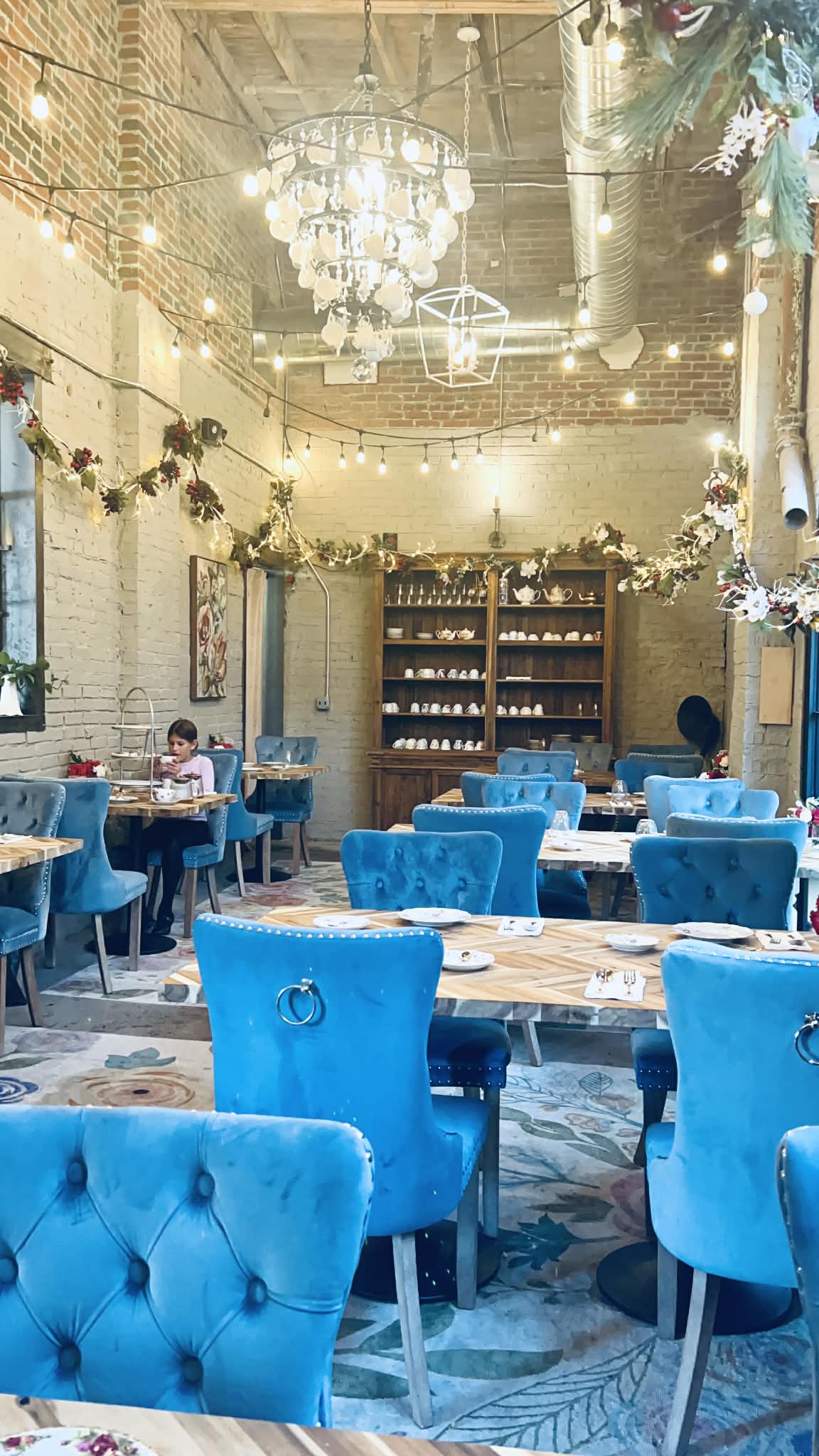 A little girl having tea on the plush blue chairs of the tea room in Nashville.