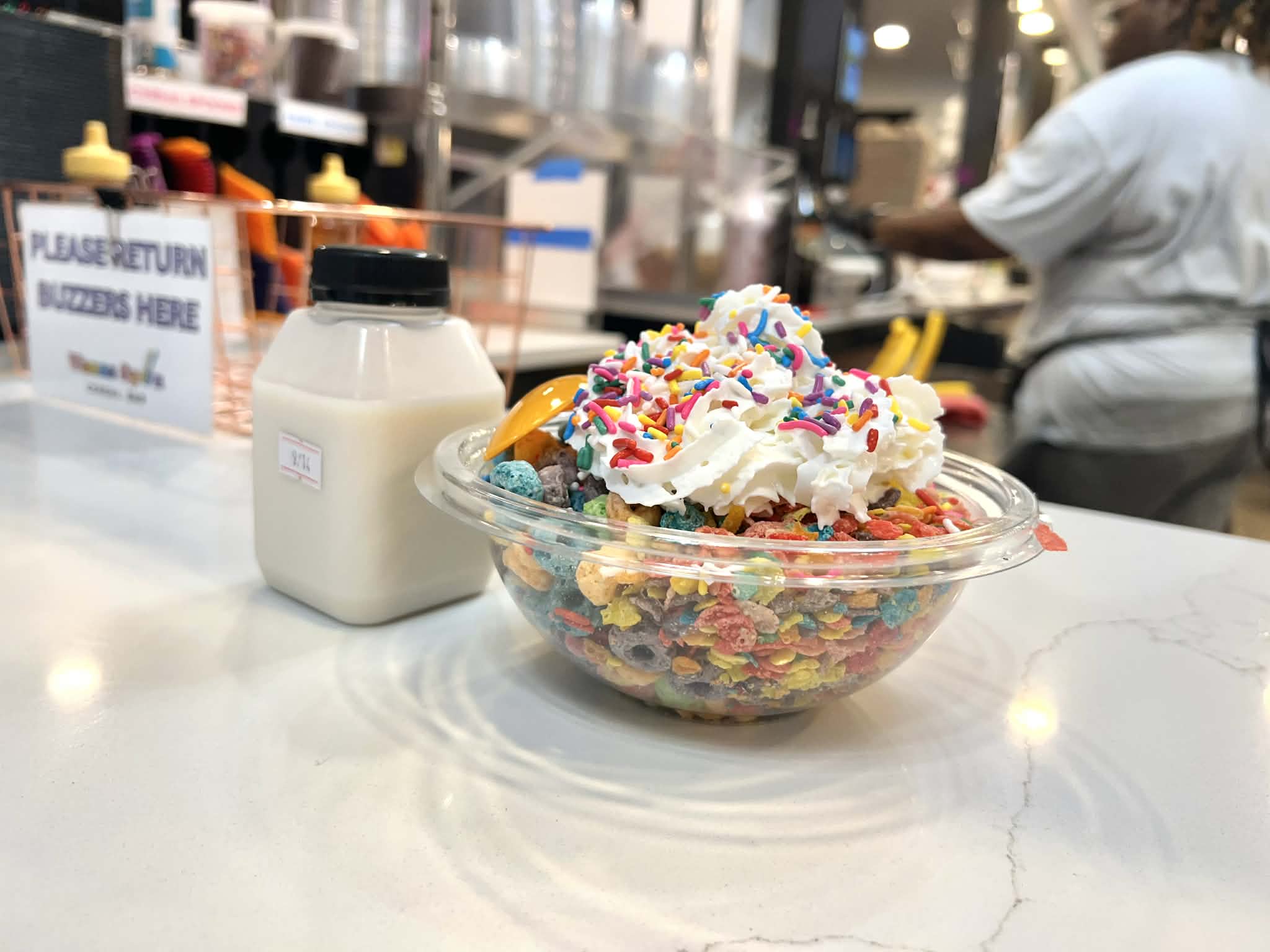 A bowl of cereal with a carton of milk.