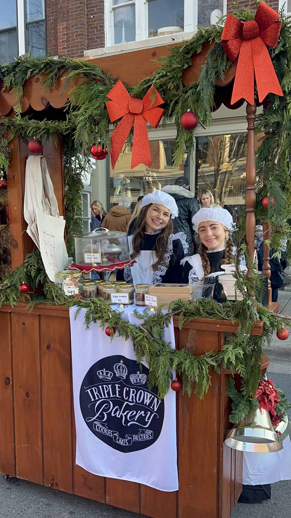 Two girls dressed in early 1900s servants outfits at a coffee cart at the Dickens of a Christmas festival.