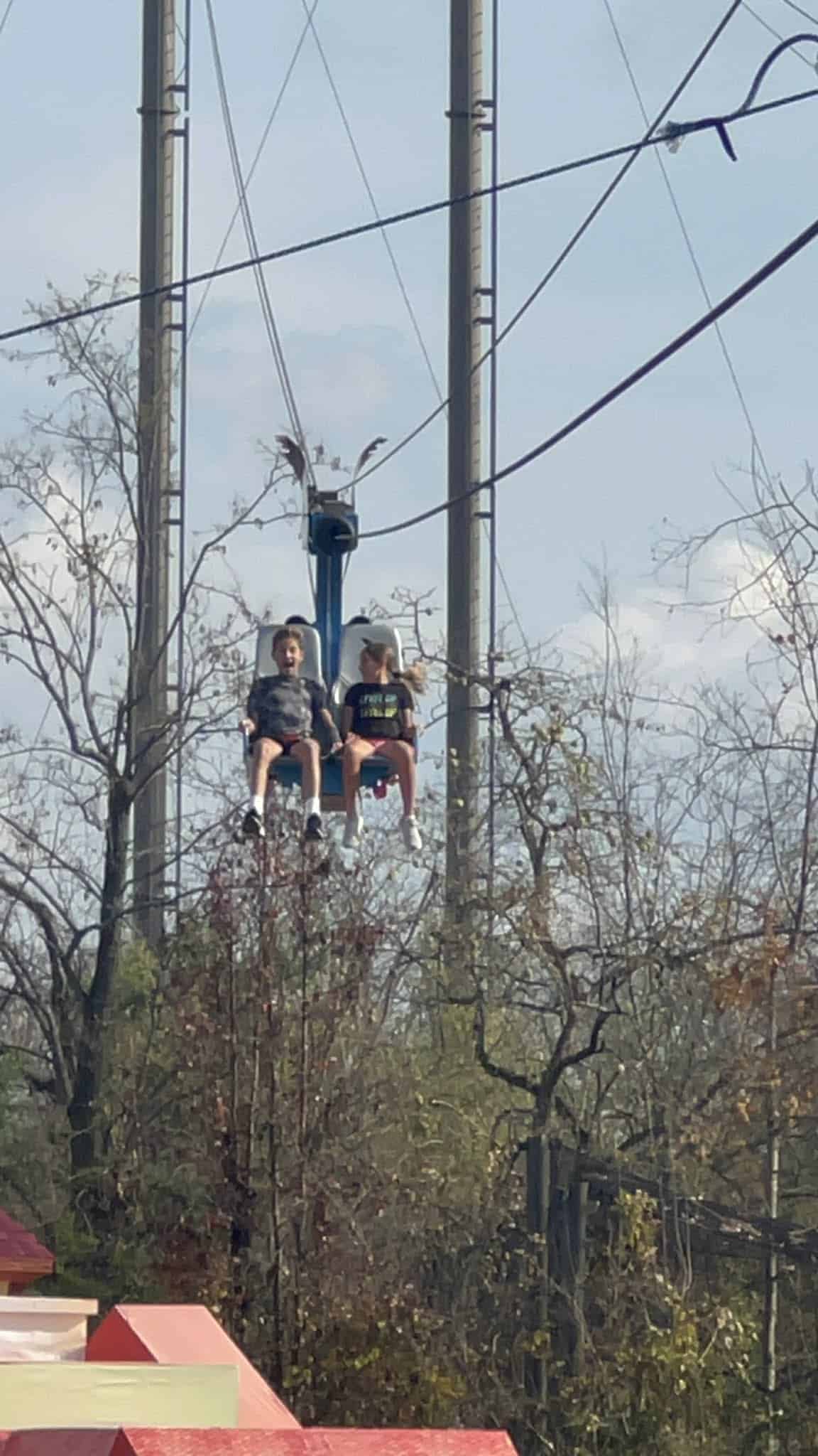 Two kids riding a chair zip-line at the Nashville zoo.