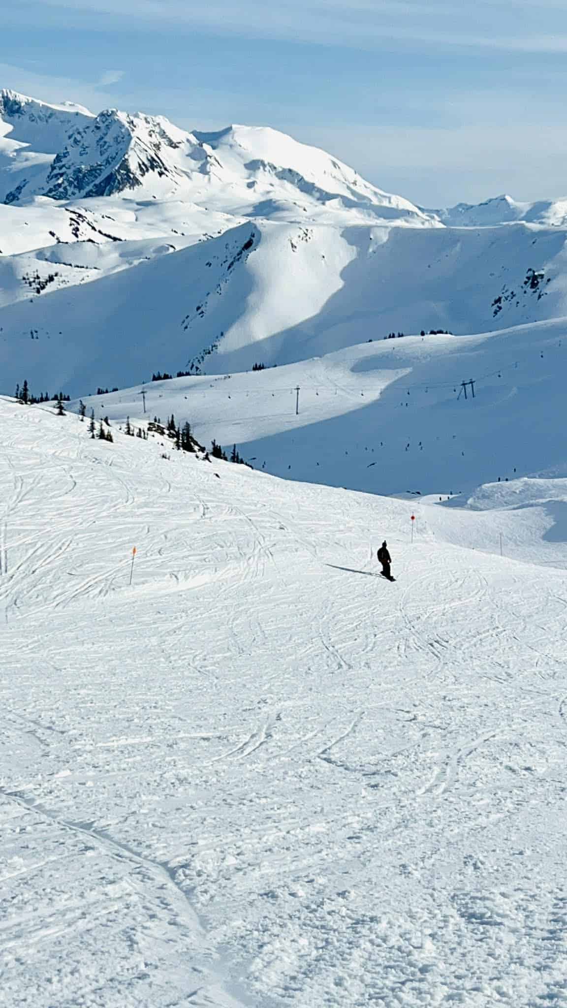 A man snowboards down Blackcomb mountain with stunning mountain views all around him.