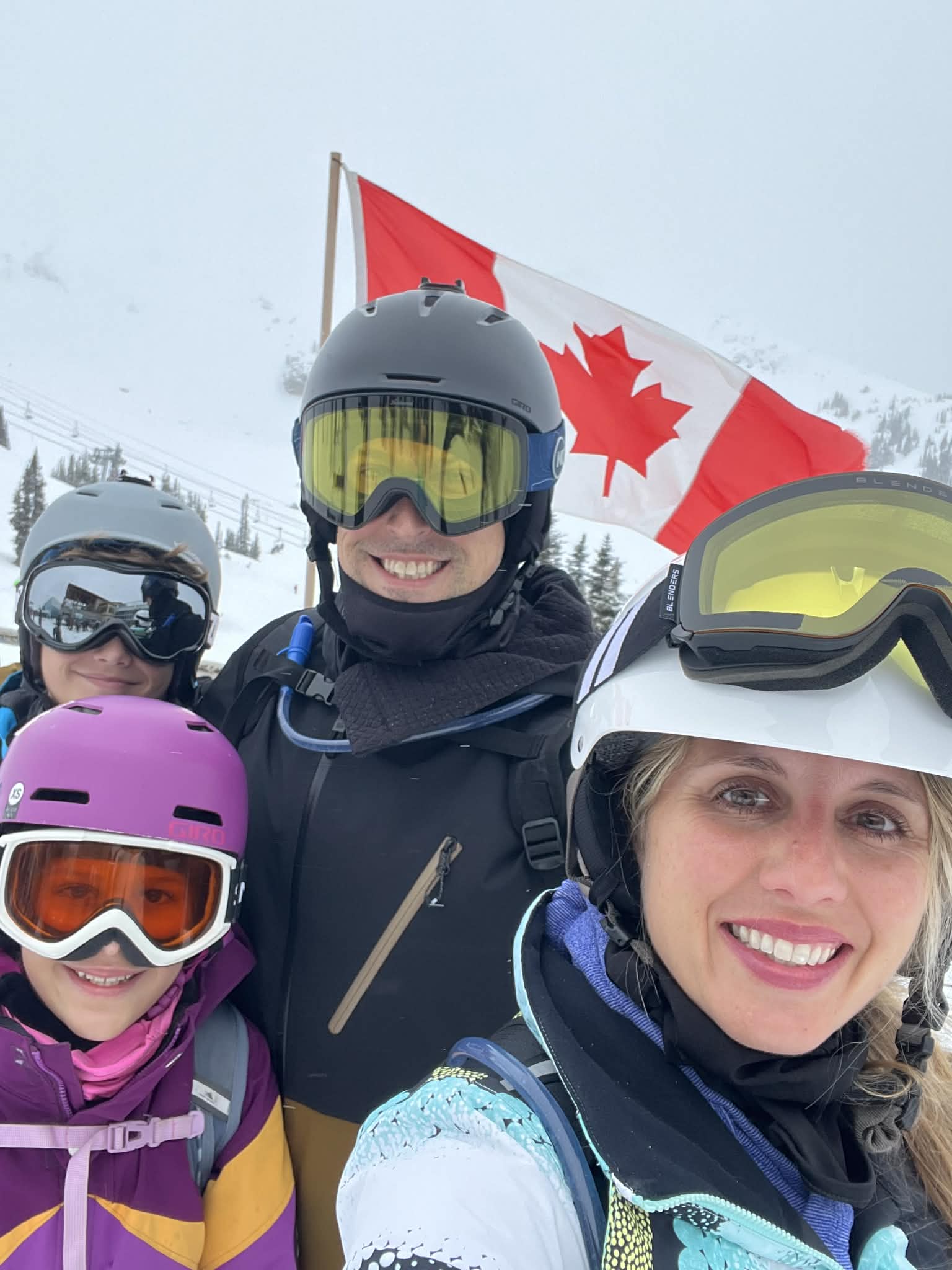 A family stands in front of the Canadian flag while in Whistler with their kids.