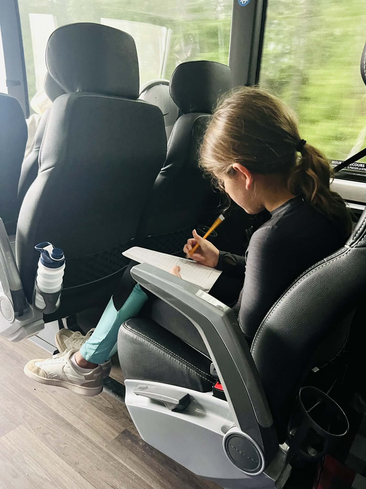 A kid writing while on the bus to Whistler.