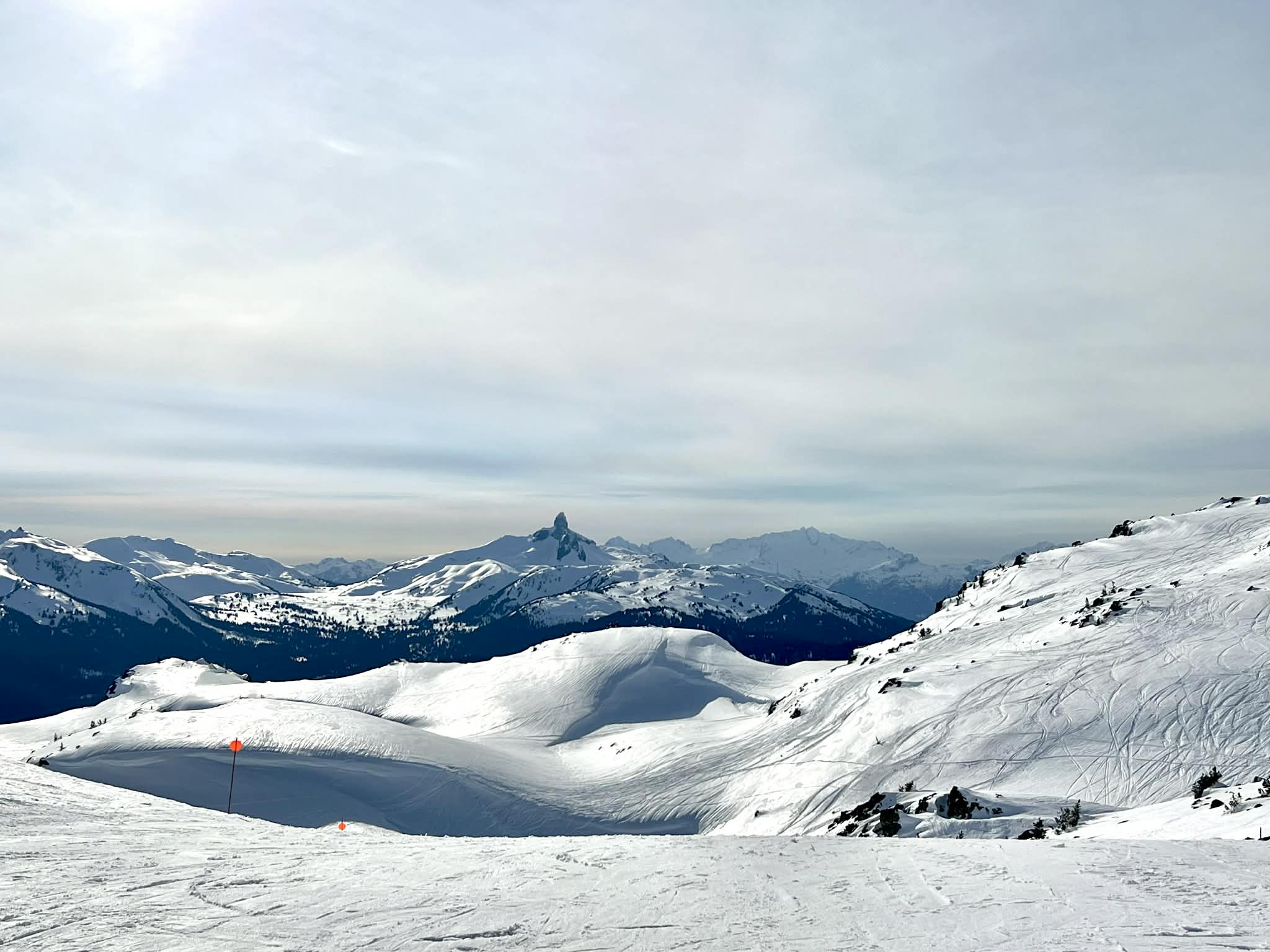 The view of a peak of a mountain and various snowy mountains all around it at the top of Blackcomb ski mountain.