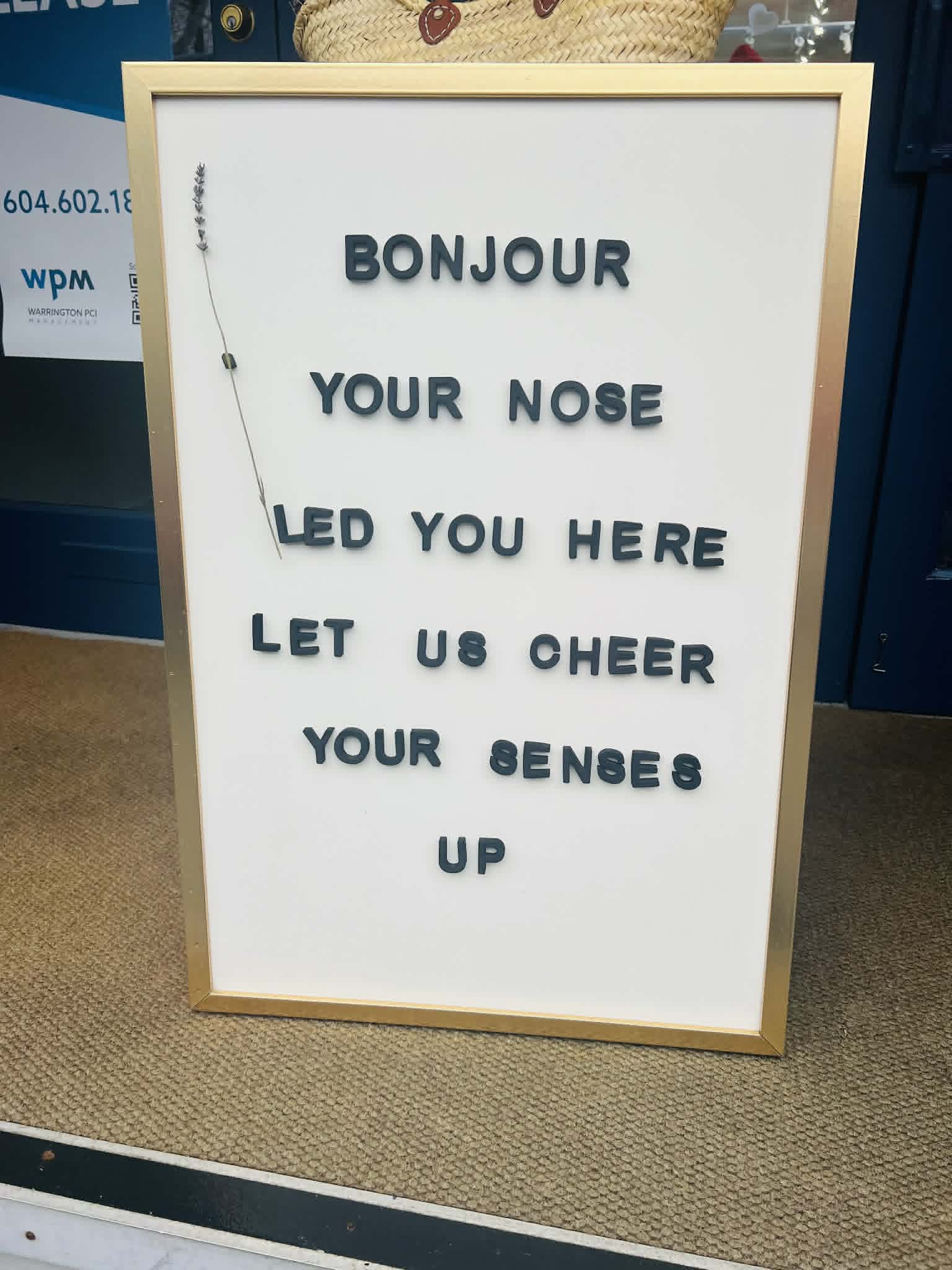 A "bonjour your nose led you here let us cheer your sense up" sign.