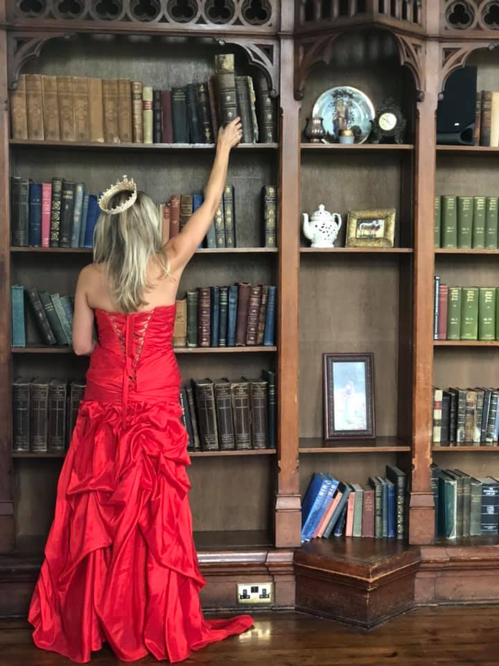A woman in the red dress reaching for a book in the Kinnitty Castle library in Ireland.