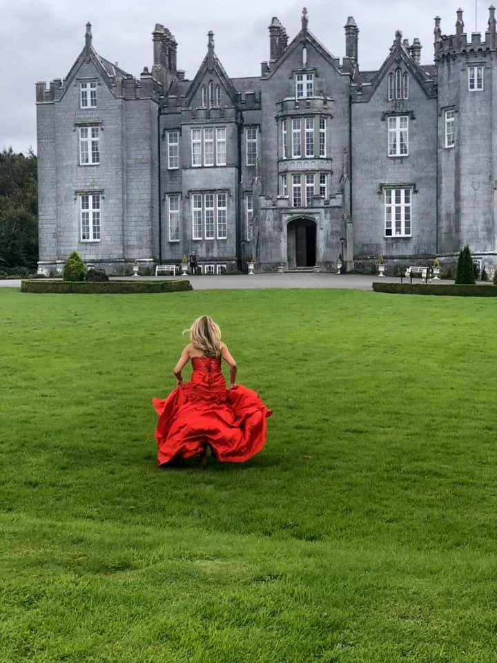 A woman in the red dress running towards the Kinnitty Castle in Ireland.