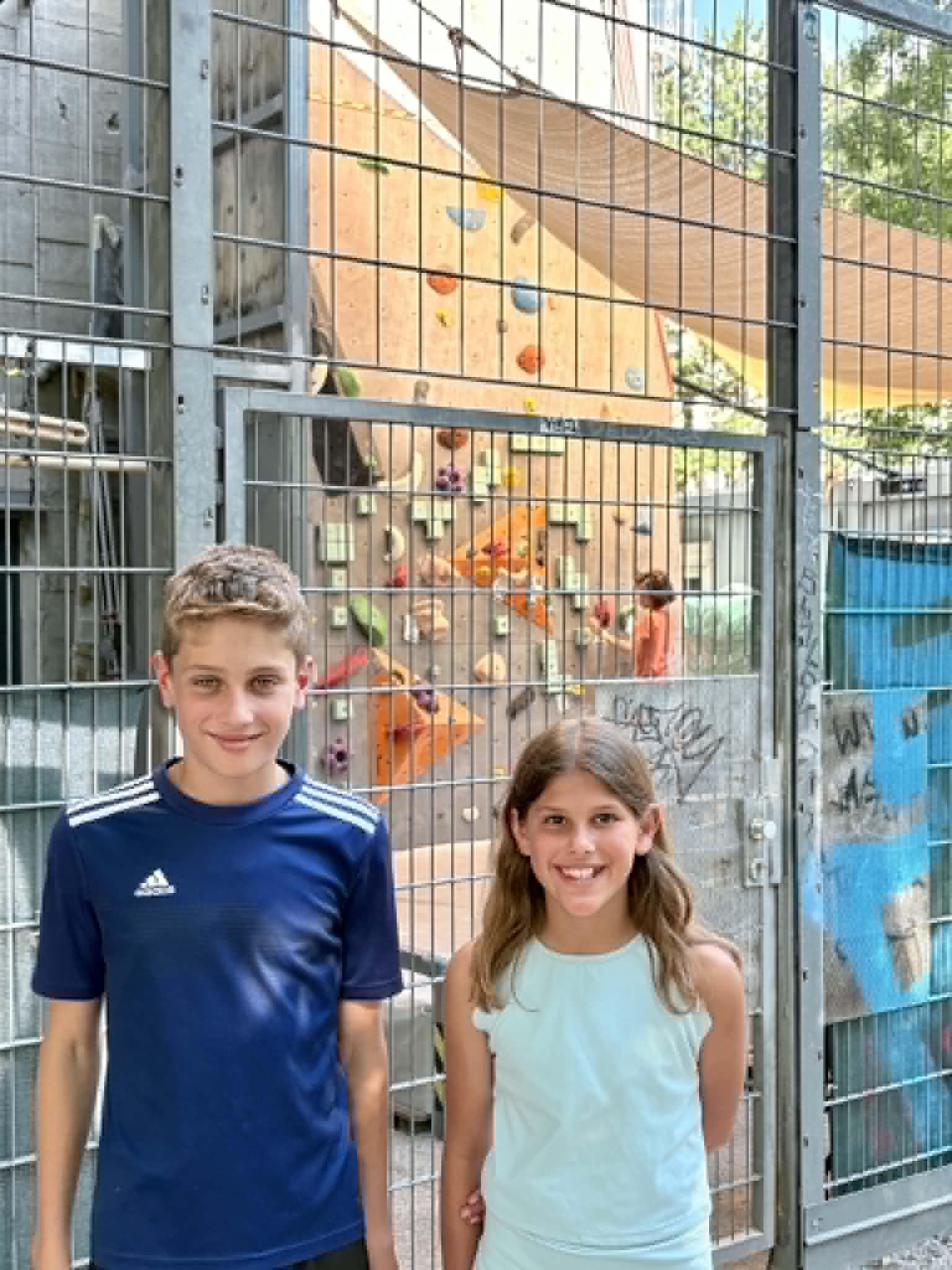 Kids next to rock climbing wall.