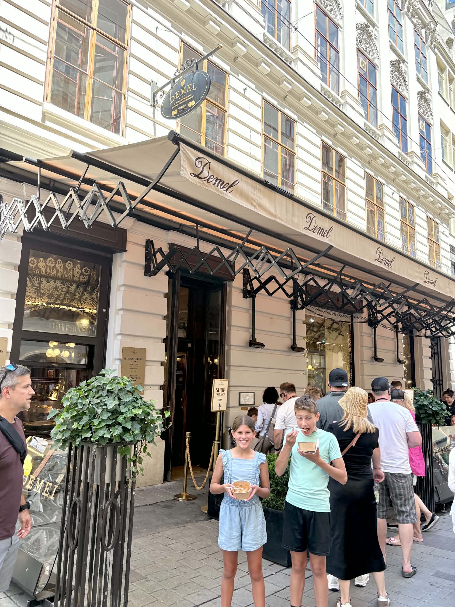 Boy and Girl in front of Demel enjoying there desserts.