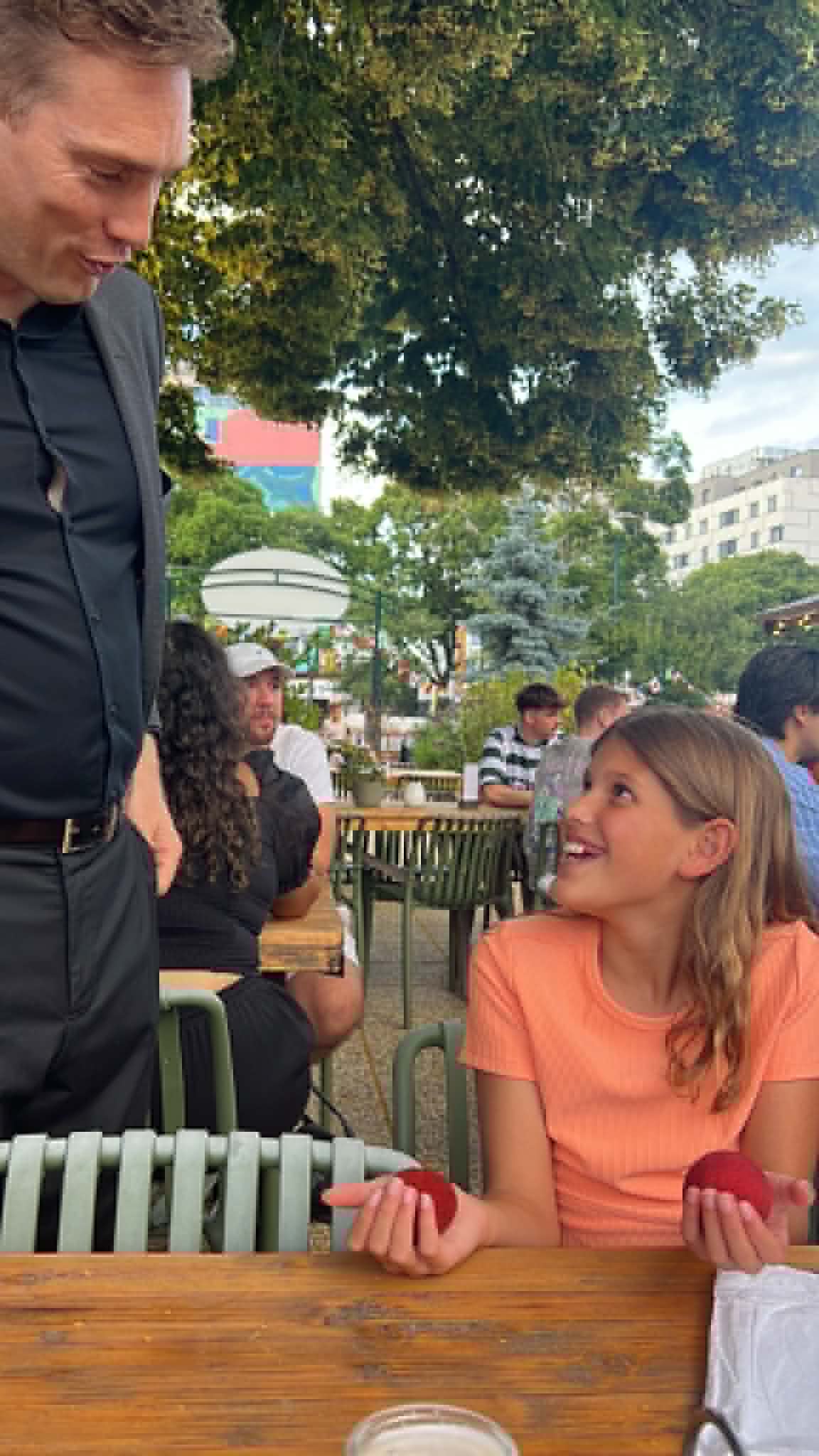 Girl smiling at a magician while holding to red balls.