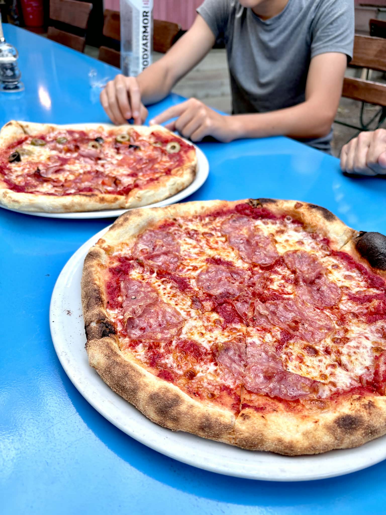 Two pizzas on a blue table at Courtside Belvoir.