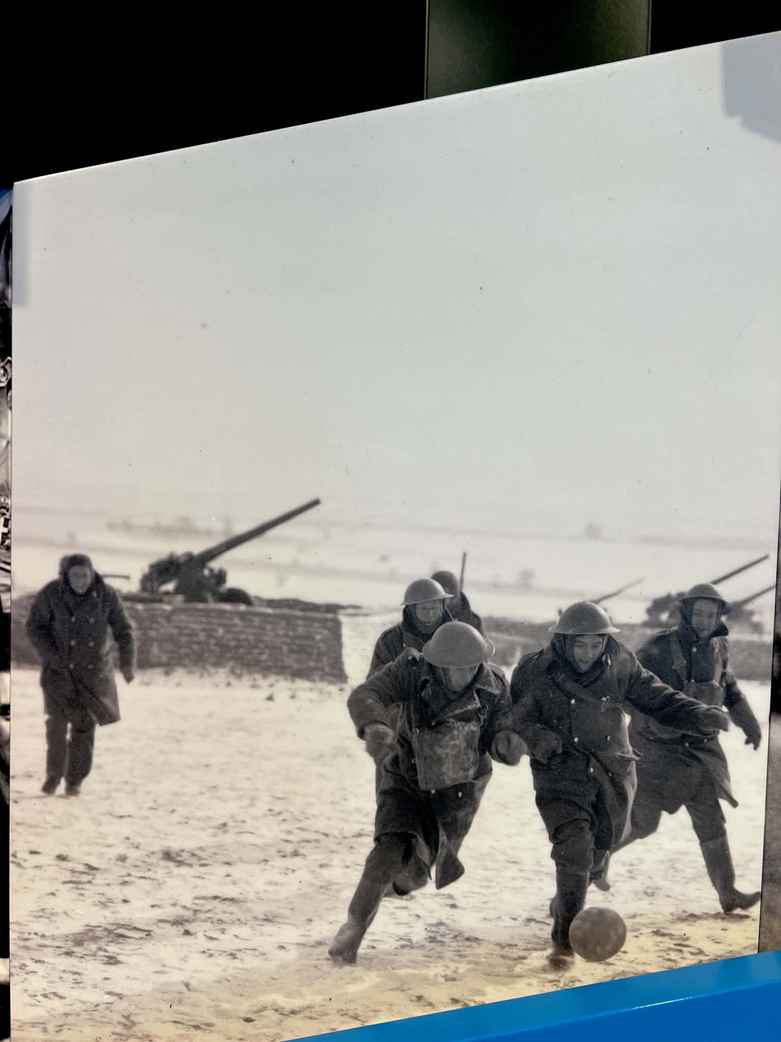 A picture in the FIFA Museum that is of people playing futbol / soccer during wartime.