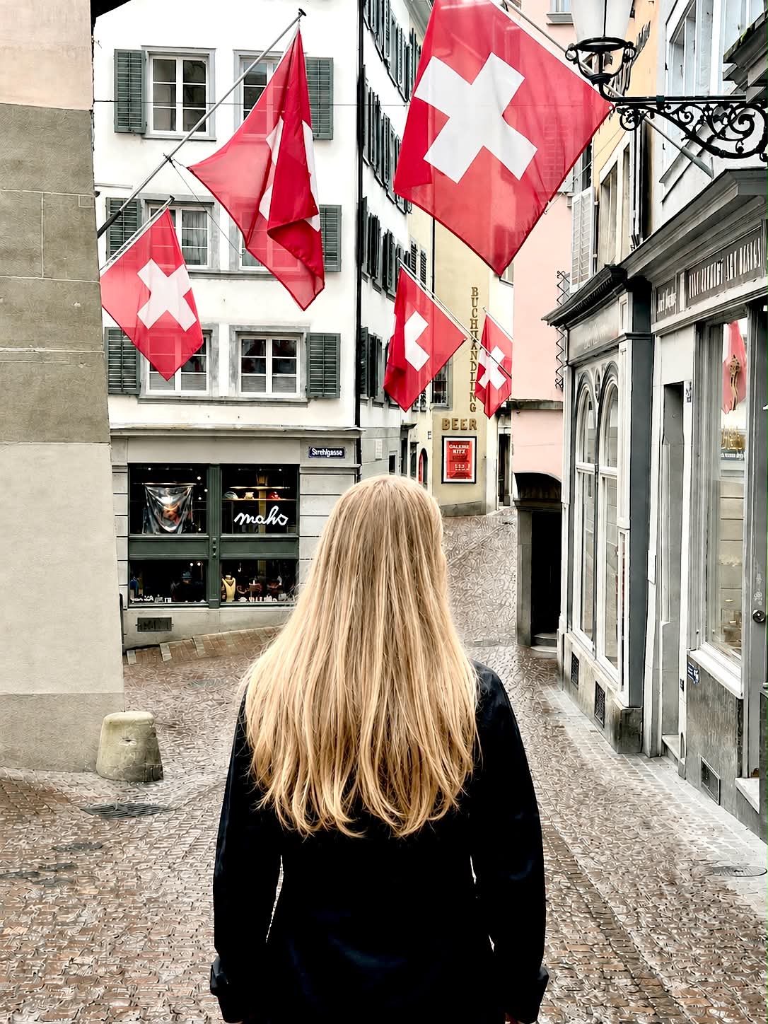 A girl standing looking at the Swiss flags in Old Town, Zurich, Switzerland.