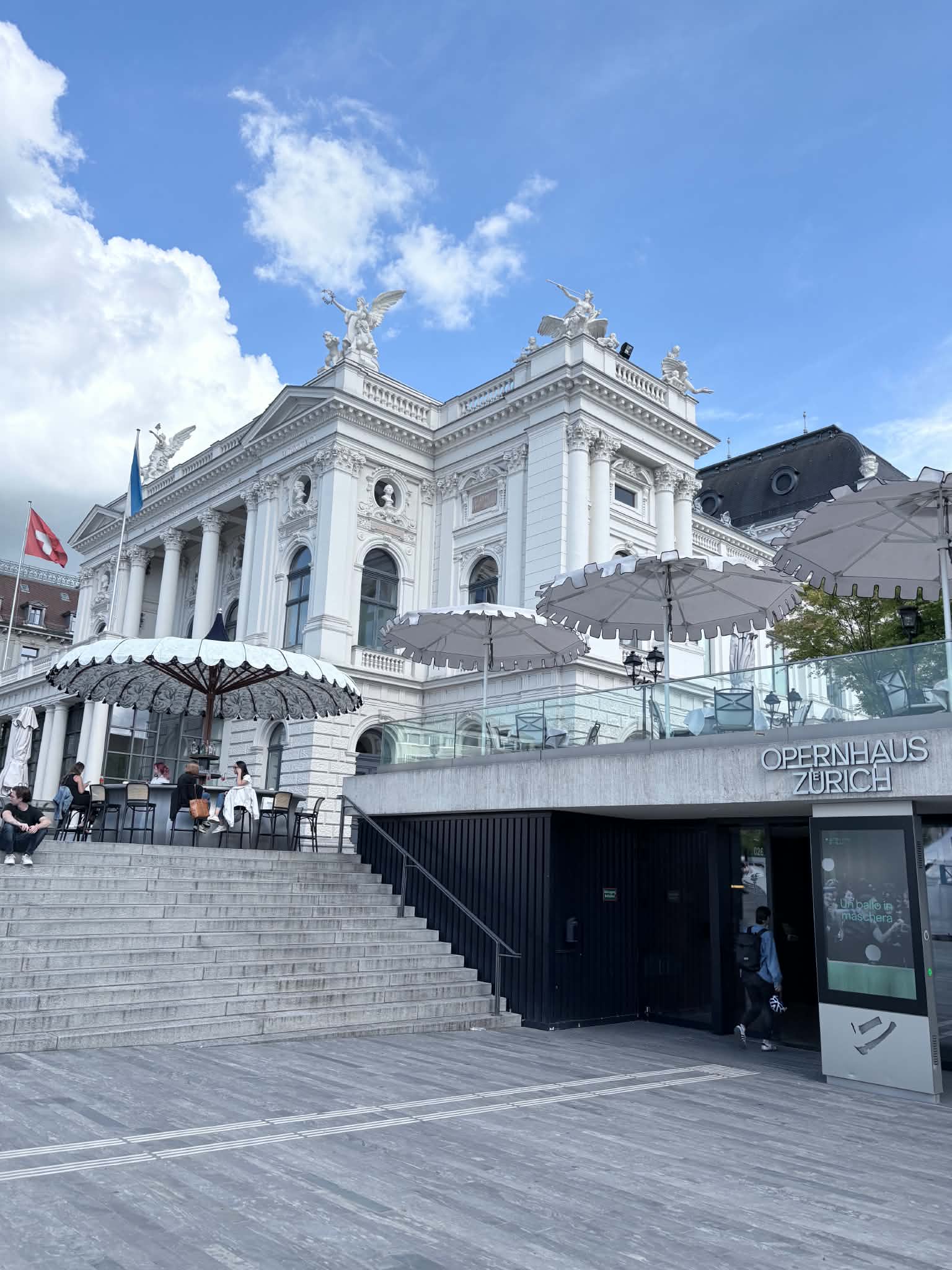 A side view of the Zurich Opera House. It is white with statues at the top.