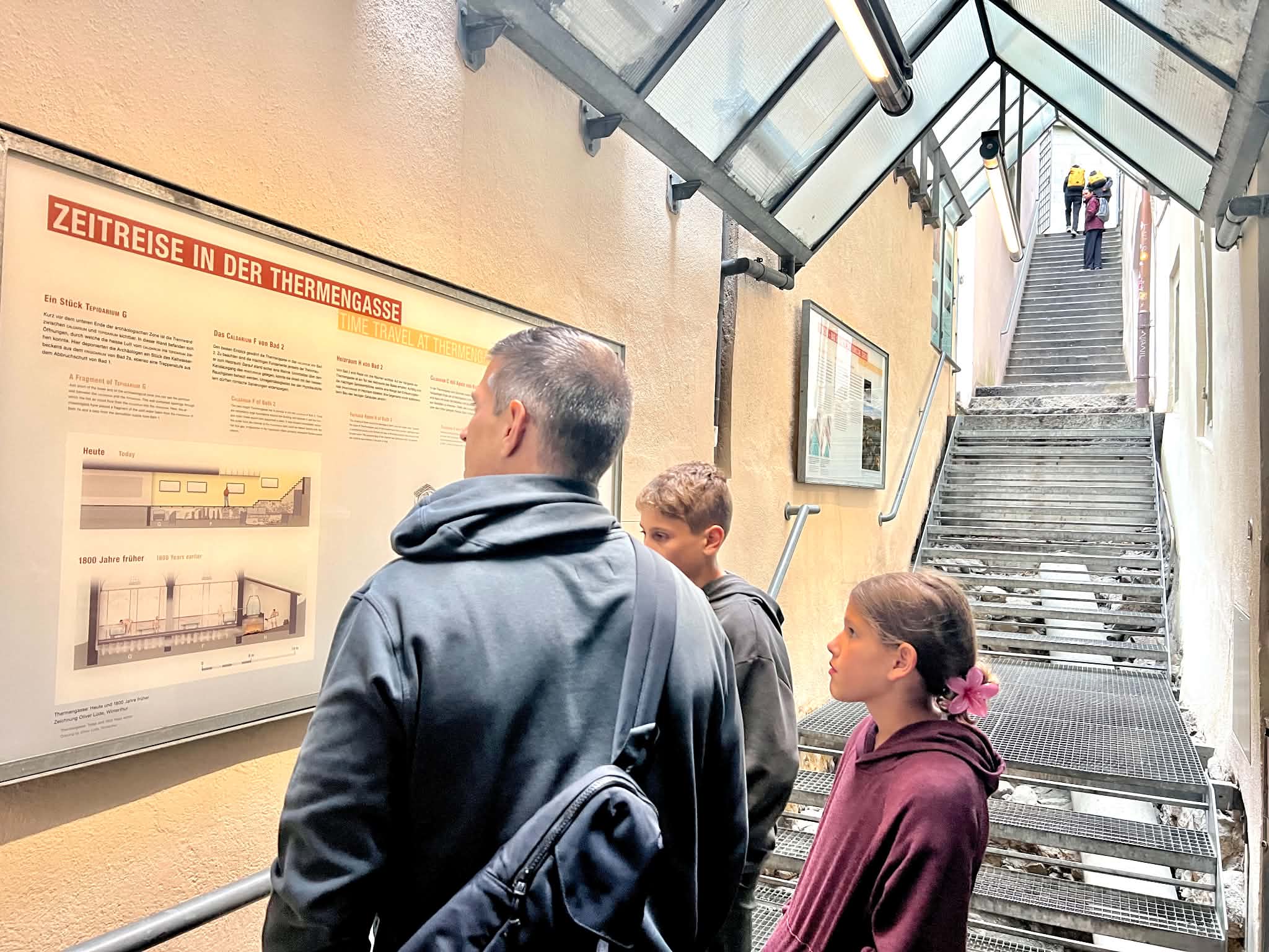 A dad in Zurich with kids looking at the information for the Archeological Windows.