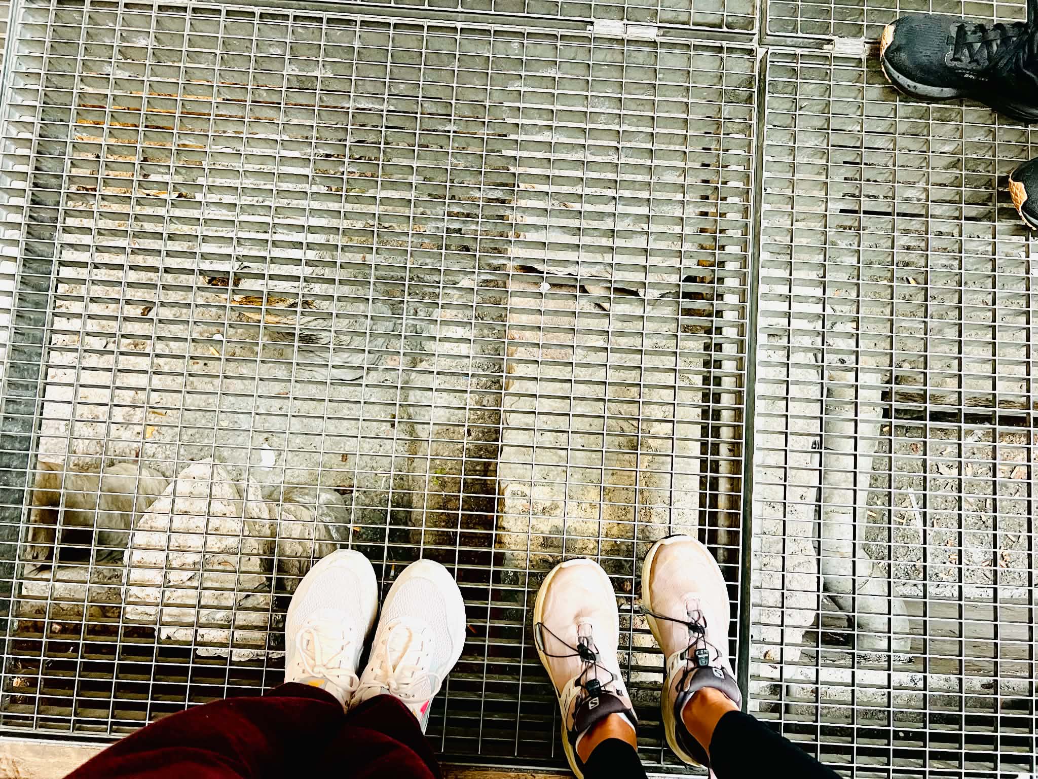 A mom and daughter's feet on a grate and underneath the grate is a view of the old Zurich bath houses.