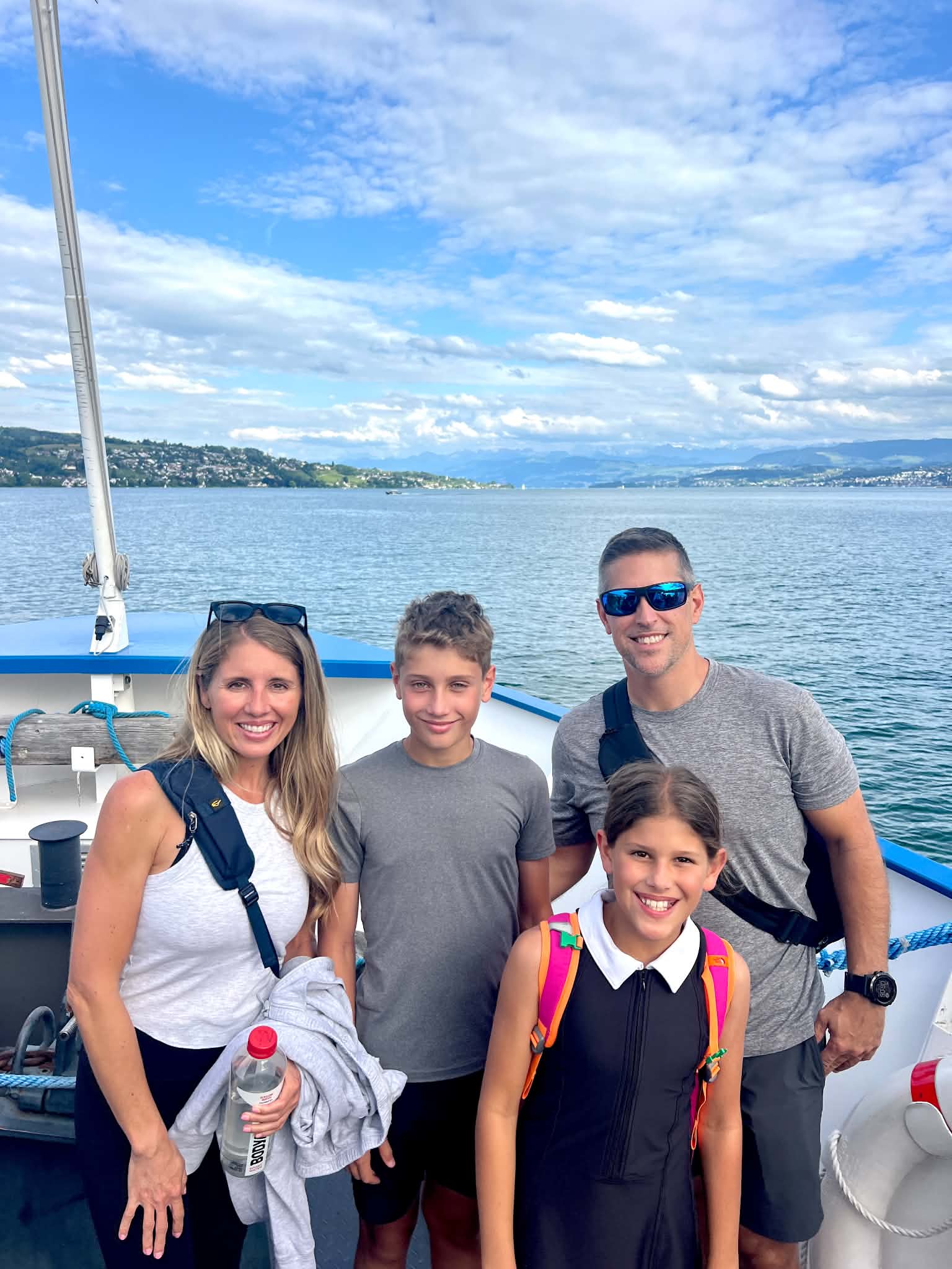 A mom and dad in Zurich with kids on a boat ride and the Swiss mountains behind them.
