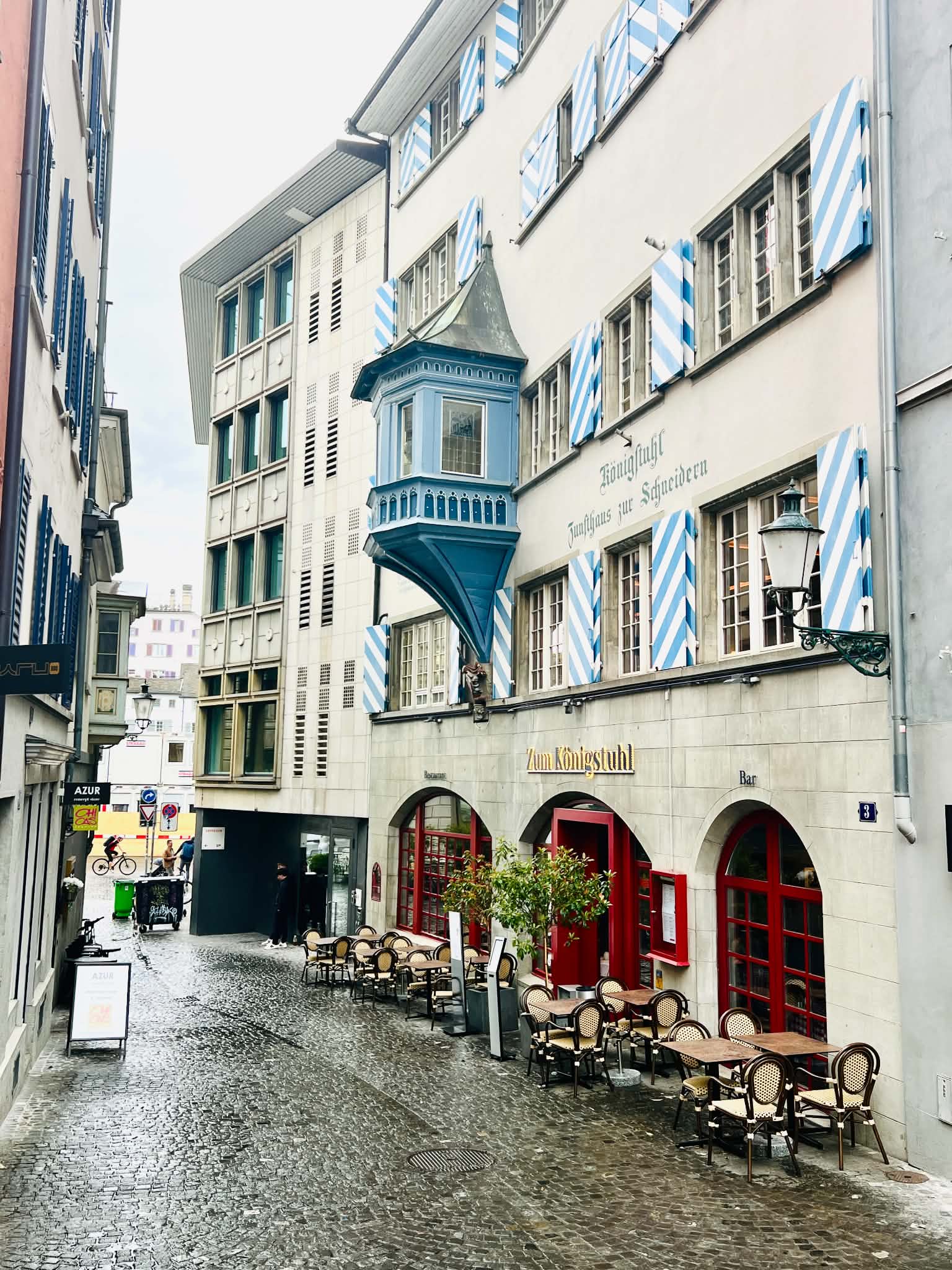 A gorgeous, old building in Zurich that has a blue window sticking out of it.