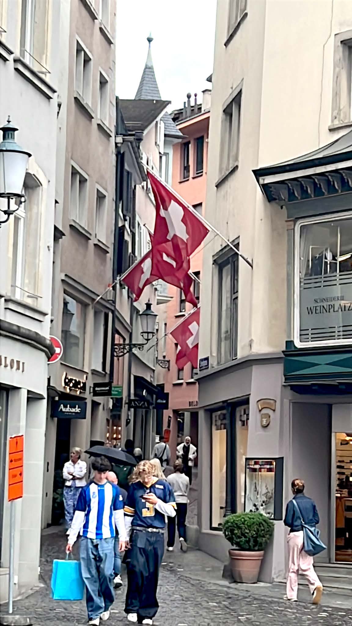 Kids in Zurich, Switzerland walking around Old Town with the Swiss flag above them.