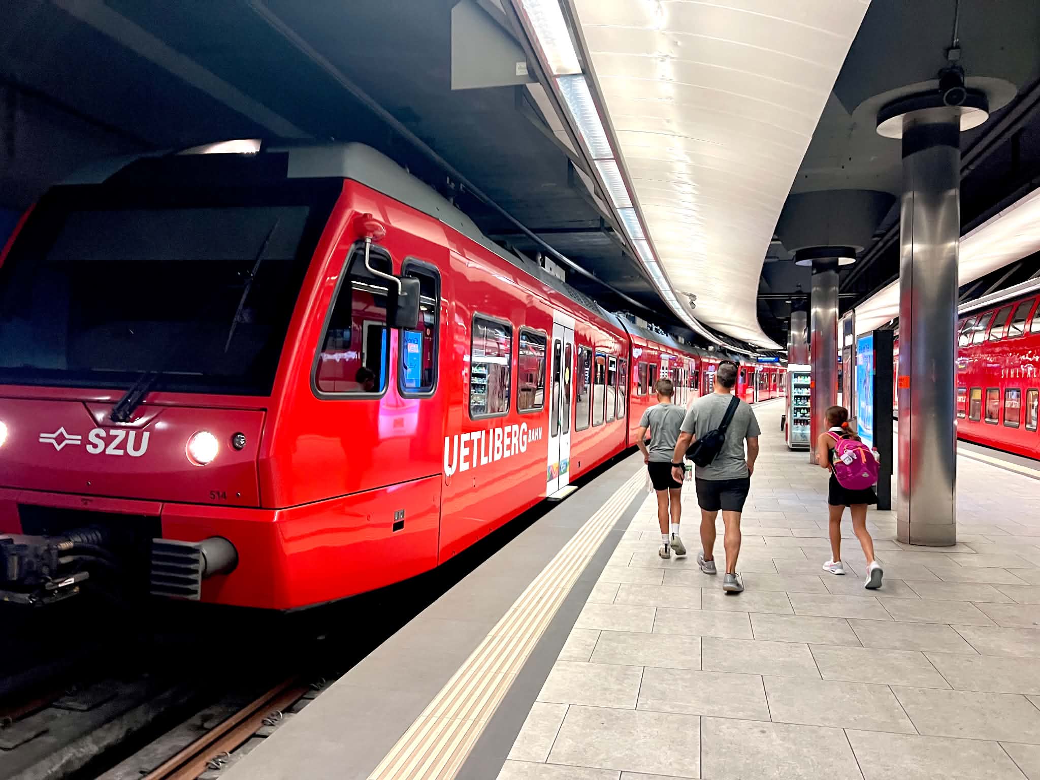 A dad in Zurich with kids getting ready to board a red train.