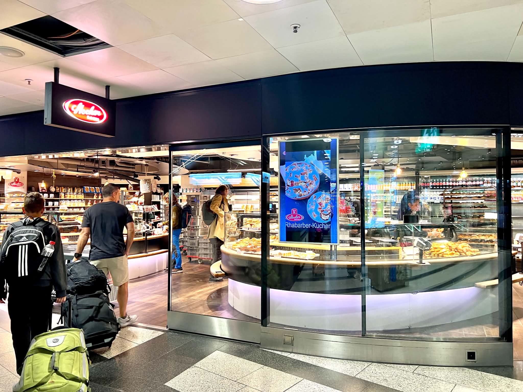 A family walking into the cafe / bakery that is in the train station in Zurich.