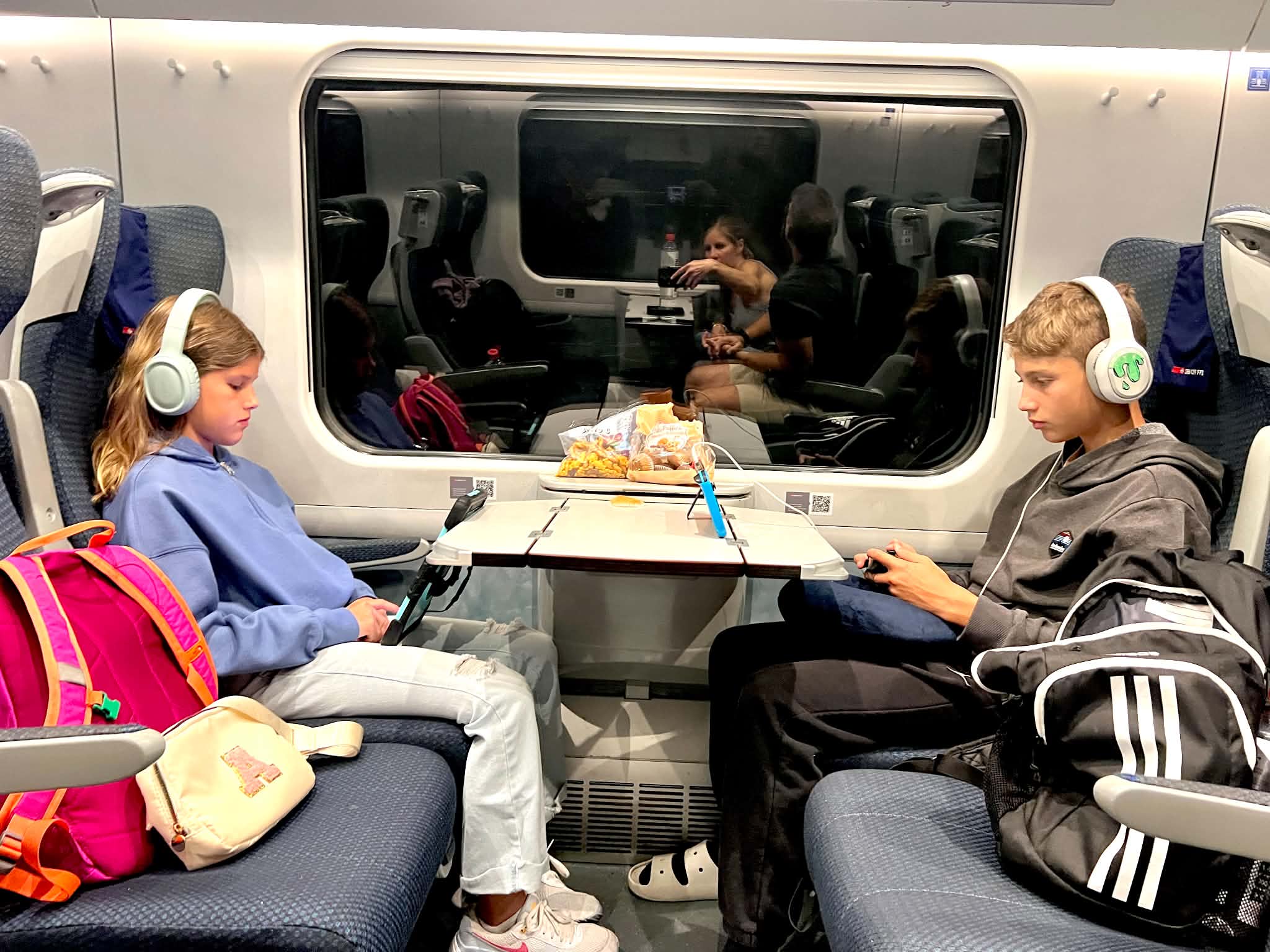 Two kids on a train leaving Zurich and heading to Munich.