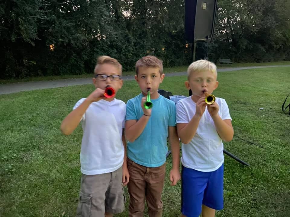 Three boys blow trumpets on Feast of Trumpets.