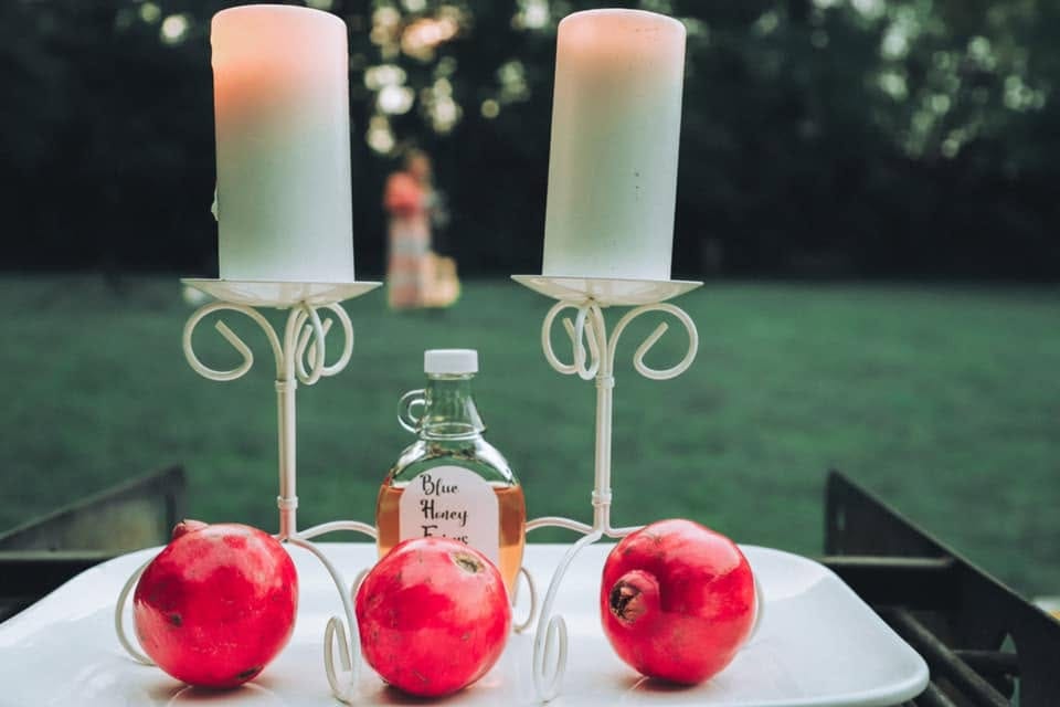 Two candles with three pomegranates and honey. A woman is presenting in the background why Feast of Trumpets is all about Jesus.